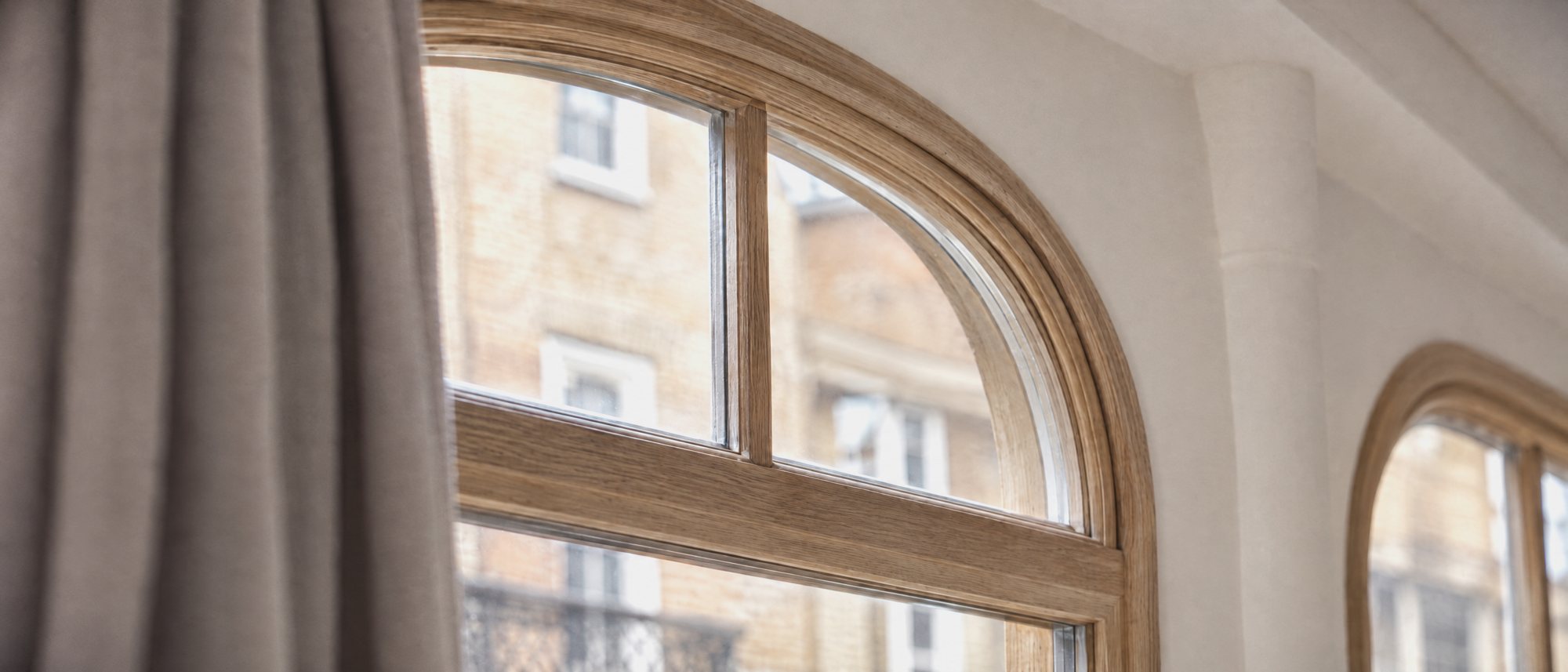 An arched window with shutters and a curtain